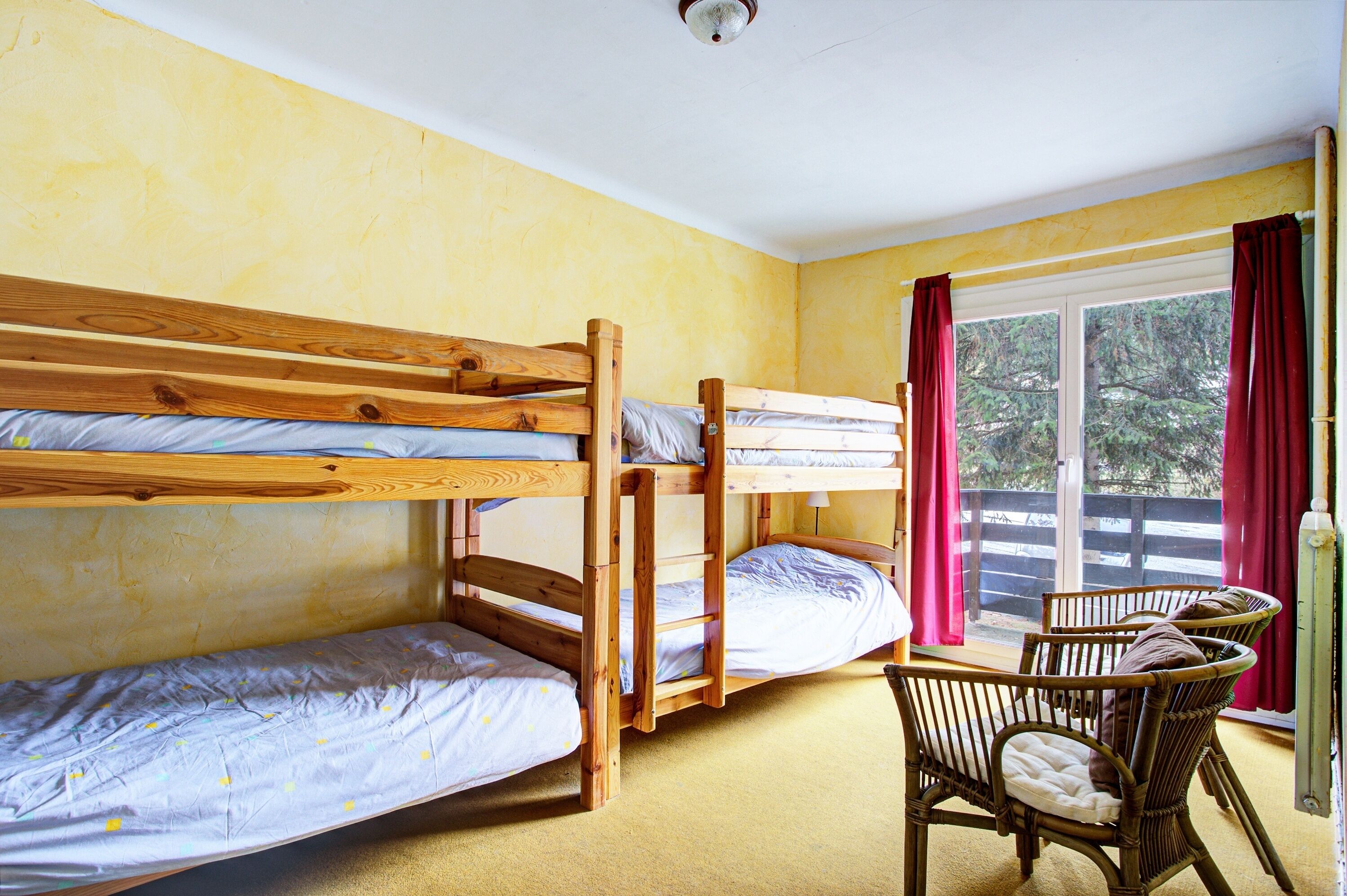 A bunk bed room with a window and a table with chairs.