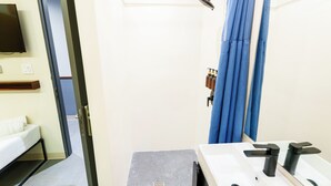 Un baño con ducha, lavamanos con espejo e inodoro.