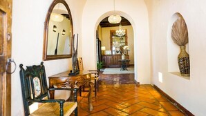 A hallway with a wooden bench, a mirror, and a chandelier. - Hotel Casa Mexicana (Mineral de Pozos)