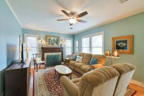 A living room with a sofa, armchairs, a coffee table, a fireplace, and a ceiling fan. - BEE Inn BRENHAM Holiday Cottage - Premium location walking distance to downtown. (Brenham)