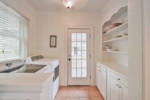 Laundry room with a washing machine and dryer, a door with a window, and storage space.