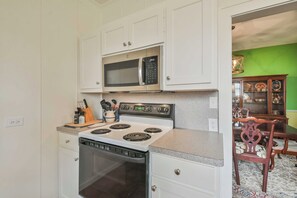 Kitchen area with modern stove, microwave, and dishwasher, adjacent to a dining space with a table and chairs.