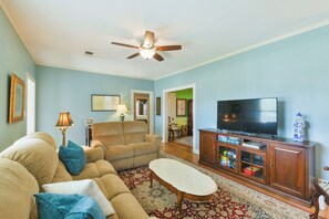 A living room with a sofa, armchair, TV, and entertainment center. - BEE Inn BRENHAM Holiday Cottage - Premium location walking distance to downtown. (Brenham)