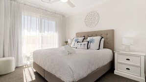 Une chambre d’hôtel avec un grand lit, une table de chevet, une lampe et un élément décoratif mural.