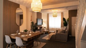 Ein modernes Wohnzimmer mit Essbereich, einer Couch und einem Fernseher.