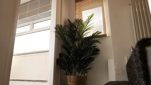 Eine Ecke des Raumes mit einem Blumentopf, einem Fenster mit Jalousien und einer Tür, die zur Garage führt.