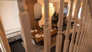 Ein Essbereich mit einem Holztisch, gedeckt für vier Personen, einem Spiegel an der Wand und einem Fernseher im Hintergrund.