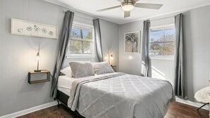 Een slaapkamer met een bed, een plafondventilator, een nachtkastje en een wandlamp.