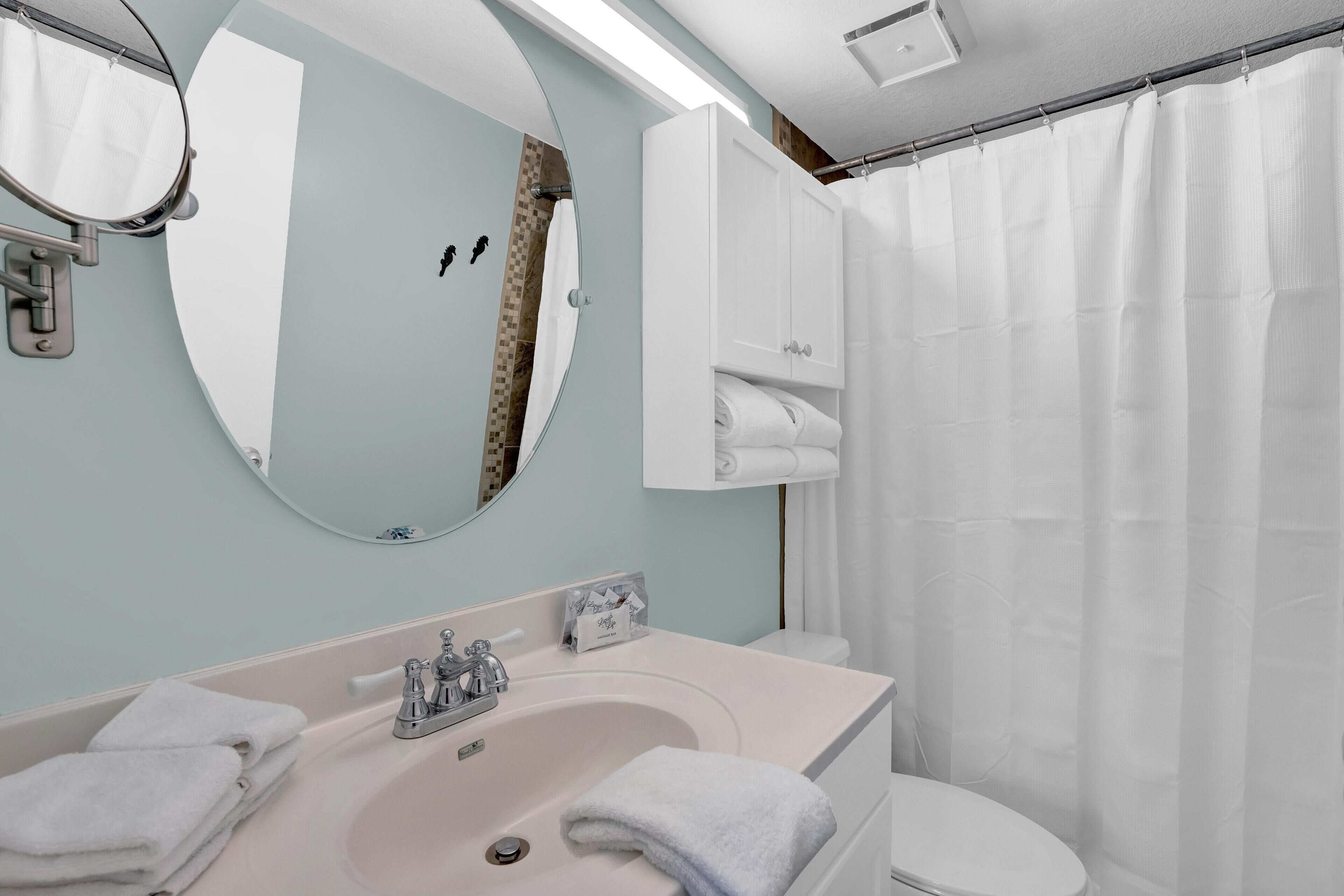 A bathroom with a sink, mirror, towel rack, and a shower curtain.