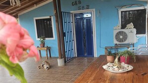 A wooden table with a plate of seashells, a dog lying on the floor, and a blue door with a gate. - Charming 2-bedroom house with WiFi, AC in Dibulla, ocean view. (Dibulla)