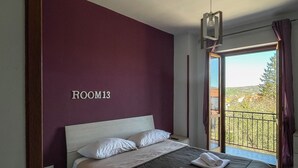 Une chambre avec un grand lit, une vue sur l’extérieur et une pancarte indiquant « CHAMBRE 13 ».