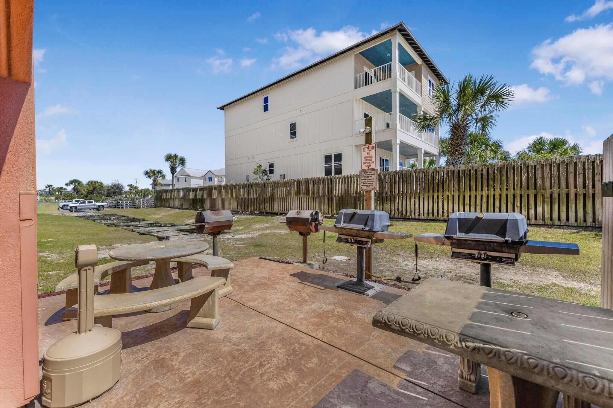 A patio area with outdoor grills, a picnic table, and a building in the background.