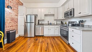 Uma cozinha moderna com armários brancos, eletrodomésticos de aço inoxidável e piso de madeira.