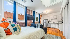 A bedroom with a bed, a sofa, a window, and a kitchen area with cabinets and appliances. - Colorful Studio in Downtown Hot Springs (Hot Springs)