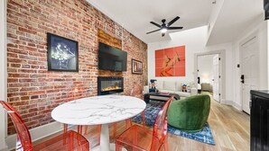 A dining area with a brick wall, a fireplace, a round table, and red chairs. - Stylish Loft in the Heart of Downtown (Hot Springs)