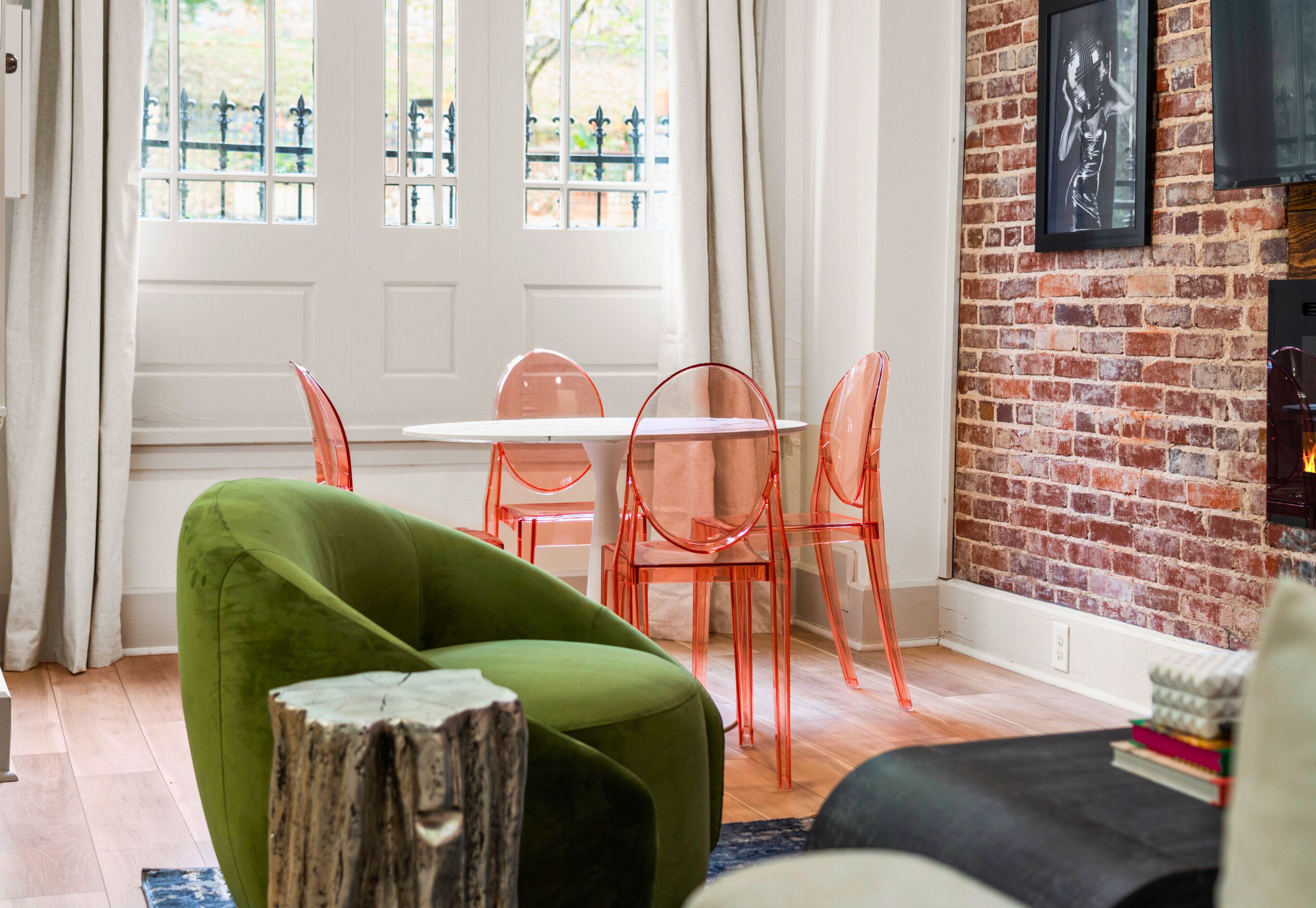 A room with a dining table and chairs, a green armchair, a brick wall, and a fireplace.