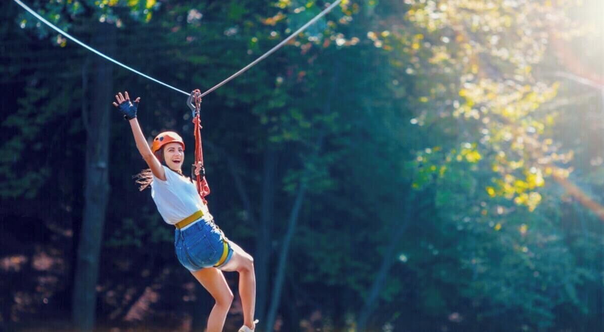 En person som åker på en zipline genom ett skogsområde.