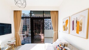 Et moderne hotelværelse med en stor seng, et skrivebord og en balkon med udsigt over byen.