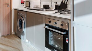 Et moderne køkken med indbyggede hårde hvidevarer, herunder vaskemaskine, ovn og mikrobølgeovn.
