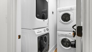 A laundry room with stacked washers and dryers, a control panel, and a 10-year warranty sticker. - Funky Bungalow Studio · Walk to Bathhouse Row (Hot Springs)