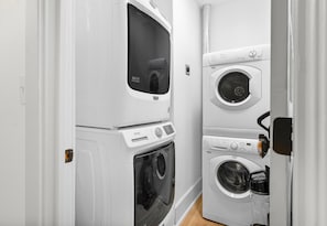 Une buanderie équipée de machines à laver et de sèche-linge superposés, d’un panneau de commande et d’un autocollant indiquant une garantie de 10 ans.