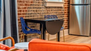 A dining area with a brick wall, a stainless steel refrigerator, and a window. - Funky Bungalow Studio · Walk to Bathhouse Row (Hot Springs)
