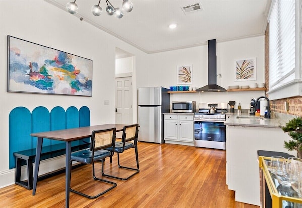 Une cuisine moderne avec un coin repas, un réfrigérateur, un four à micro-ondes, une cuisinière et un banc bleu.