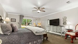 A bedroom with a bed, a television, a ceiling fan, a dresser, and a chair. - 3 BR, Tiled Showers, Hot Tub, King Bed, Smart TV (Fredericksburg)