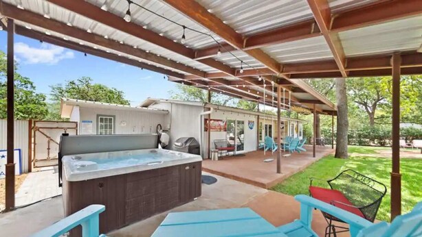 A covered patio area with a hot tub, outdoor seating, and a barbecue grill. - 3 BR, Tiled Showers, Hot Tub, King Bed, Smart TV (Fredericksburg)