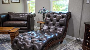 Una sala de estar con un sillón de cuero marrón oscuro, una mesa de centro de madera y una alfombra estampada.