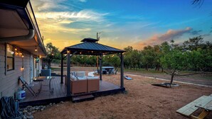 A covered patio area with outdoor furniture, a small table, and a grill. - 6 BR Private Ranch, 2 Hot Tubs, Game Barn (Fredericksburg)