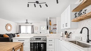 Una cocina moderna con armarios blancos, una estufa de acero inoxidable y un horno negro.