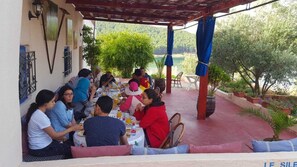 A group of people dining at an outdoor table with a view of the surrounding landscape. - Le relais de tahla  (Smià)