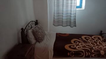 Quarto com cama, mesa de cabeceira, janela com cortinas e parede com textura.