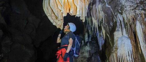 A person standing on a rock inside a cave with stalactites.