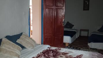 A room with a bed, a wooden door, and two bedside tables.