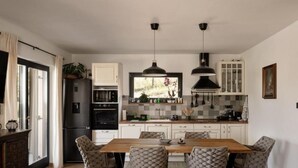 Una cocina moderna con una isla central, armarios blancos e iluminación colgante.