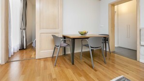 A room with a wooden floor, a table with two chairs, a basket of fruit, and a door leading to another room. - Charming Bright Gem Rovinj Downtown - Two Bedroom Apartment with Terrace (Rovinj)
