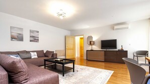 A modern living room with a brown sofa, a coffee table, and a TV on a stand. - Charming Bright Gem Rovinj Downtown - Two Bedroom Apartment with Terrace (Rovinj)