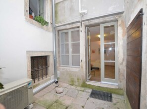 Enter a cozy room with a bed and small table, surrounded by a tranquil courtyard.