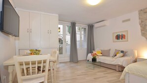 Un espacio habitable compacto con comedor, kitchenette y cama.