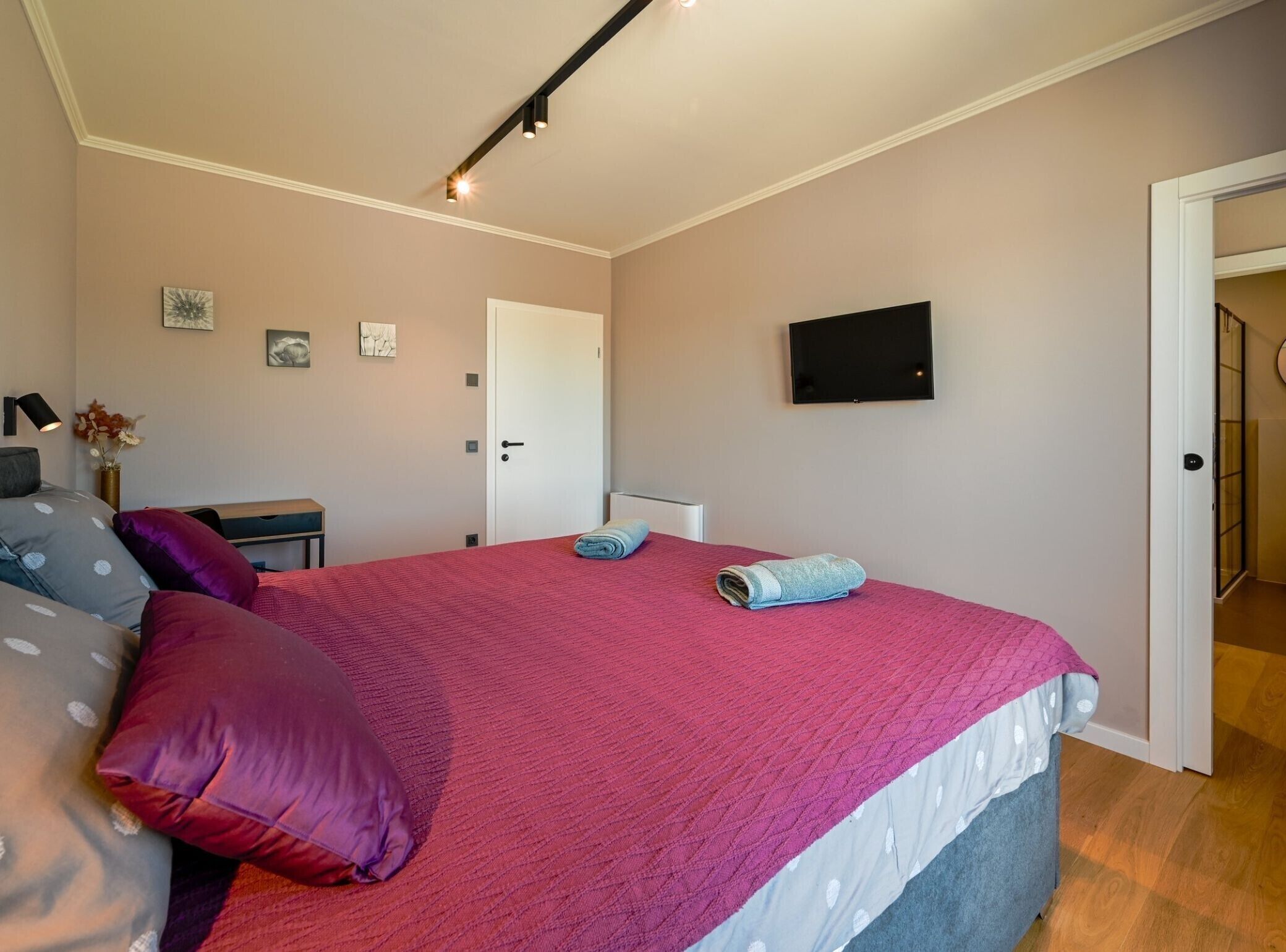 Une chambre à coucher avec un lit, des oreillers, une télévision et une porte.