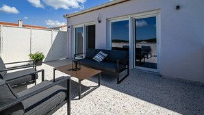 Une terrasse sur le toit avec un canapé, une table et des chaises.