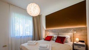 Un dormitorio moderno con una cama grande, una lámpara de techo redonda y una mesita de noche con lámpara.