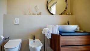 Un baño moderno con un bidé, un lavabo con encimera azul y un mueble de tocador de madera.