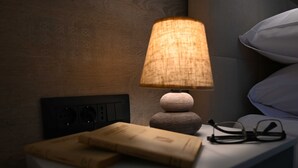 Una mesita de noche con una lámpara, un libro y gafas.
