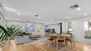 A spacious living area with a sofa, dining table, chairs, and a TV. - Rye Botanica-Swim Spa, renovated, amazing garden (Rye)