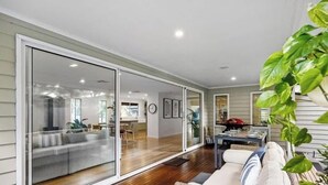 A modern living room with a sliding glass door leading to a dining area. - Rye Botanica-Swim Spa, renovated, amazing garden (Rye)