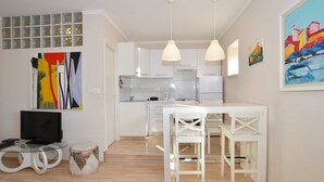 Eine moderne Wohnung mit Küche, Essbereich und Wohnzimmer. Es gibt einen Fernseher, einen kleinen runden Tisch und ein Sofa.