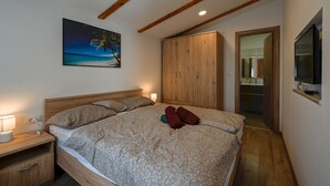 A bedroom with a bed, wooden headboard, a nightstand with a lamp, a painting of a beach scene, and a wooden wardrobe. - Rovinj Countryside Escape Holiday Home - Two Bedroom Holiday Home with Terrace (Rovinj)